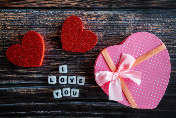 Ροζ καρδιά σχήμα κουτί δώρου Ημέρα του Αγίου Βαλεντίνου σε ξύλινο τραπέζι με I Love You κείμενο και αντίγραφο χώρου. - Φωτογραφία, εικόνα