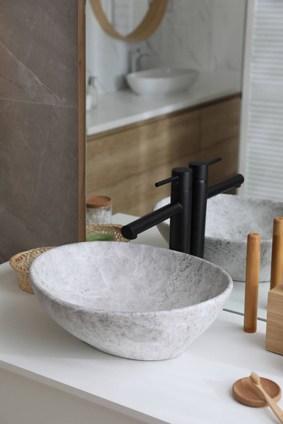 Stone vessel sink with faucet and toiletries on white countertop in bathroom - Valokuva, kuva