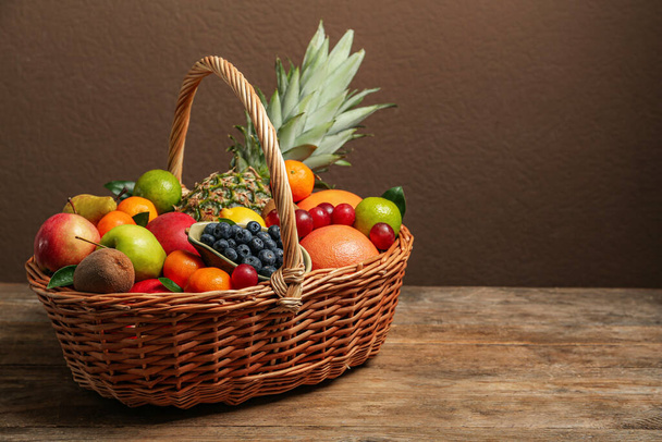 Assortment of fresh exotic fruits in wicker basket on wooden table. Space for text - Φωτογραφία, εικόνα