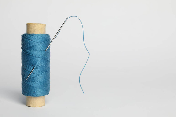 Light blue sewing thread with needle on white background - Zdjęcie, obraz