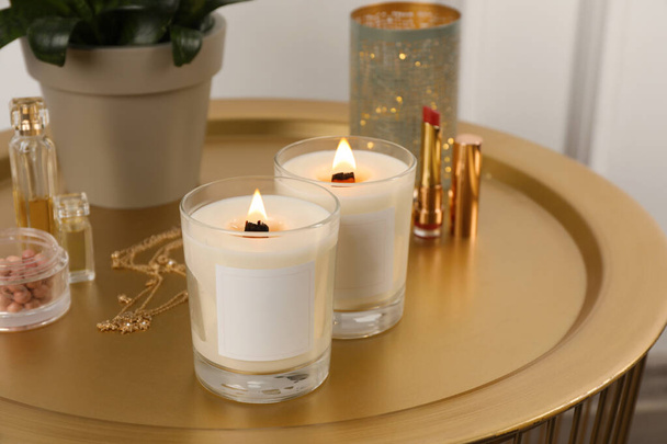 Burning soy candles, cosmetics and stylish accessories on table indoors - Foto, afbeelding