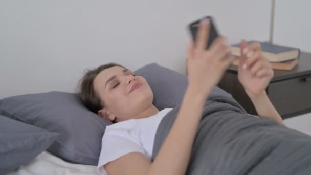 Γυναίκα που μιλάει στο Smartphone ενώ κοιμάται στο κρεβάτι - Πλάνα, βίντεο