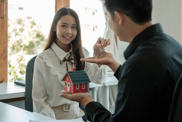 real estate agent holding house key to his client after signing contract agreement in office,concept for real estate, moving home or renting property - Photo, Image