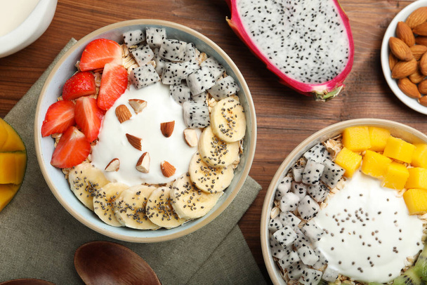 Bowls of granola with yogurt and fruits on wooden table, flat lay - Foto, Imagem
