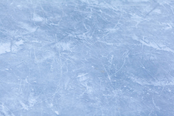 Lege ijsbaan met schaatssporen na de sessie outdoor. ijsbaan textuur bedekt met sneeuw bij daglicht. Close-up van blauwe ijsbaan vloer, kopieerruimte - Foto, afbeelding