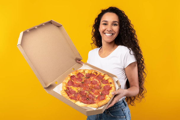 Happy Latin Lady Holding Pizza Offering To Camera - Foto, afbeelding