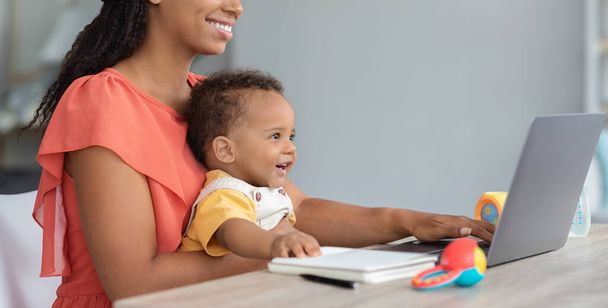 Çocuklar ve Teknolojiler. Siyah bebek evde annesiyle dizüstü bilgisayar kullanıyor. - Fotoğraf, Görsel