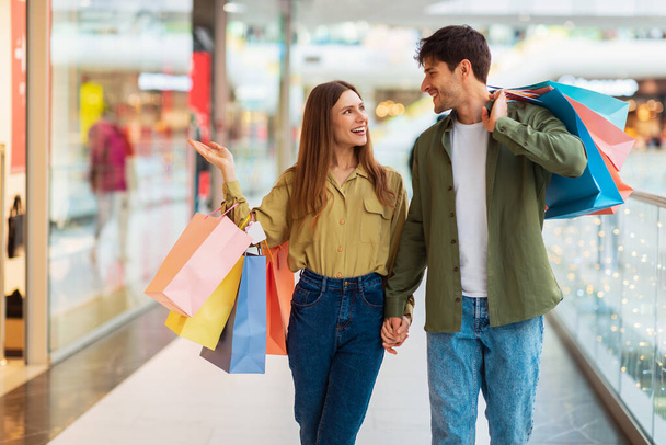 Familienpaar geht gemeinsam einkaufen, Ehefrau zeigt Bekleidungsgeschäft in Einkaufszentrum - Foto, Bild
