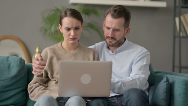 Ζευγάρι αντιδρώντας στην απώλεια στο φορητό υπολογιστή, ενώ κάθεται στον καναπέ  - Πλάνα, βίντεο