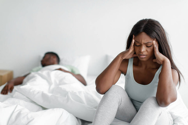 Depressed despaired sad young african american female suffers from snoring sleeping guy, lady covers ears - Zdjęcie, obraz