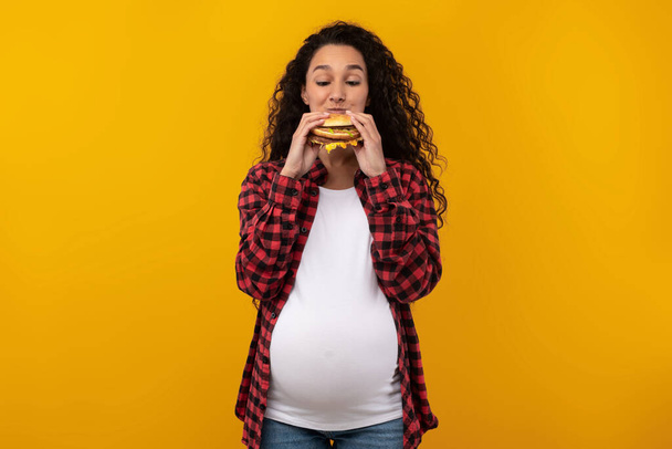 Funny Pregnant Latin Lady Holding Burger Biting Sandwich At Studio - Photo, Image