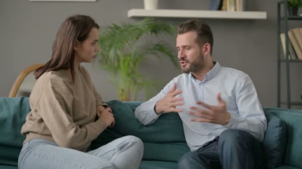 Hombre serio hablando con la mujer mientras está sentado en el sofá
  - Metraje, vídeo