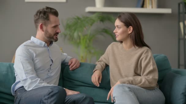 Мужчина разговаривает с женщиной, сидя на диване  - Кадры, видео