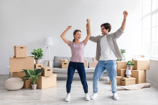 Feliz hombre milenario europeo y señora bailando en el interior de la sala de estar con cajas de cartón - Foto, imagen