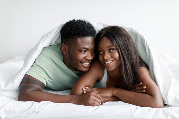 Porträt des lächelnden fröhlichen Millennial afrikanisch-amerikanischen Mann und Frau aufwachen genießen zärtlichen Moment - Foto, Bild