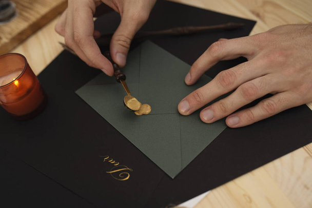 Male hands sealing dark green envelope with wax - 写真・画像