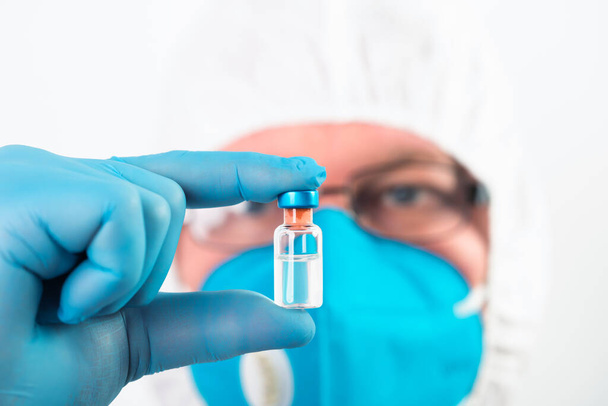 COVID-19 coronavirus vaccine. Vaccination concept. Doctor's hand in blue gloves hold medicine vaccine vial bottle and syringe.  - Foto, immagini