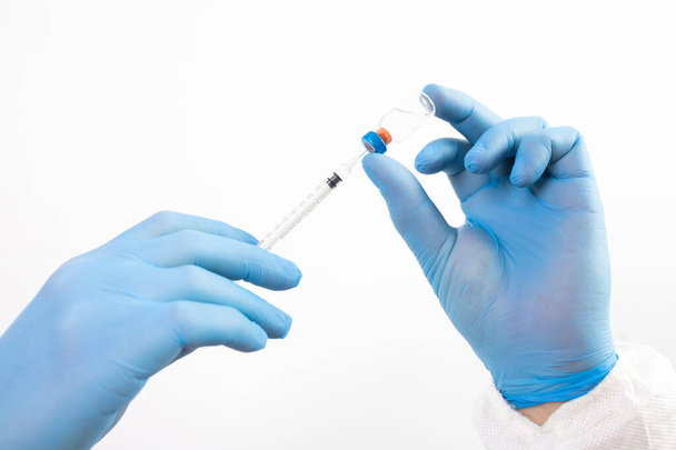 COVID-19 coronavirus vaccine. Vaccination concept. Doctor's hand in blue gloves hold medicine vaccine vial bottle and syringe.  - Foto, afbeelding