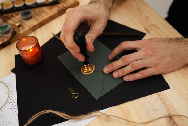 masculine hands sealing dark green envelope with wax - Foto, Bild