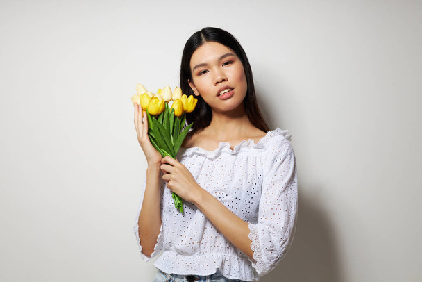 Portrait Asian beautiful young woman in a white shirt flowers spring posing light background unaltered - Фото, зображення