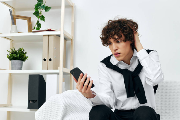 curly guy on the couch with the phone internet Lifestyle technology - Foto, Imagen