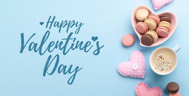 Zelfgemaakte macarons, koffiebeker en hartvormige inrichting. Top uitzicht plat lag met Happy Valentijnsdag groeten - Foto, afbeelding