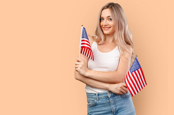 Portrait of a young woman holding USA flag isolated on color background - Foto, immagini
