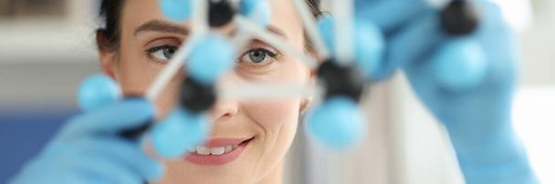 Mujer científica mira en primer plano diseño de ADN - Foto, imagen
