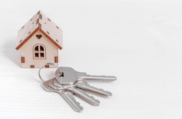 De sleutels van het huis of appartement en het huis op de achtergrond. - Foto, afbeelding