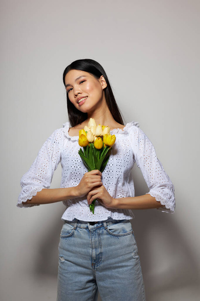 Portrait Asian beautiful young woman romance bouquet of flowers near the face light background unaltered - Fotó, kép
