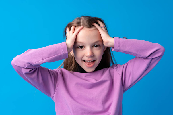 Shocked little girl looking with amazement on blue background - Fotó, kép