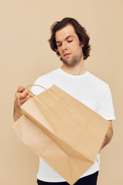 Cheerful man in a white T-shirt with paper bag Lifestyle unaltered - Foto, Imagem