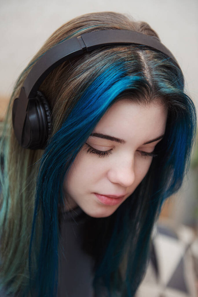 Молодая девушка-подросток с голубыми волосами и наушниками  - Фото, изображение