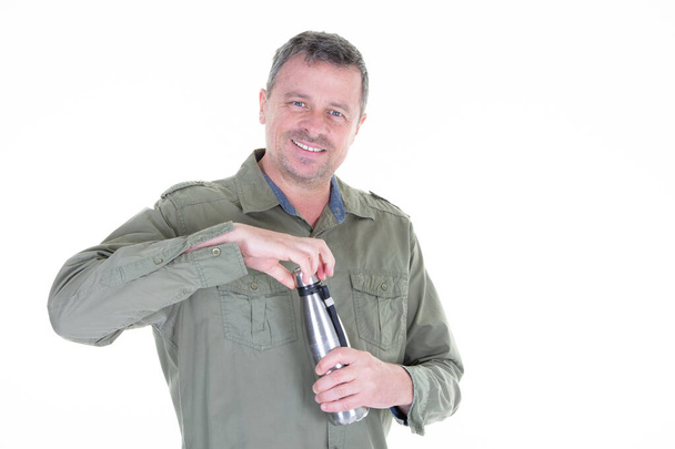 中年男性の笑顔飲料は、持続可能かつゼロ廃棄物の概念で隔離された白い背景に再利用可能なスチールボトルを保持します - 写真・画像