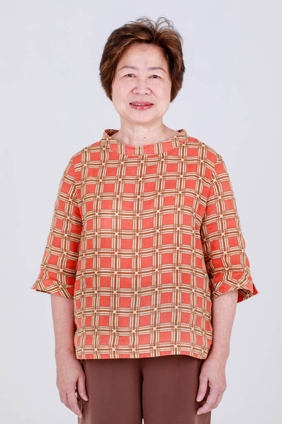 Encantadora mujer china senior se ve saludable y alegre en la camisa de tela casual de patrón comprobado como traje elegante de edad avanzada para la amabilidad madre. La abuela se ve feliz y relajarse para un estilo de vida positivo. - Foto, Imagen