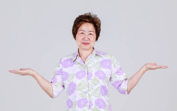 Femme chinoise âgée drôle agissant étonnamment en levant la main vers le haut et serrez le poing en criant à haute voix comme excitant à merveilleux jeu et profiter de soutenir la concurrence en tant que partisan de fan senior. - Photo, image