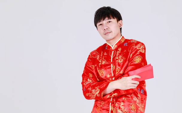 Lucky Chinese man op traditionele mandarijn shirt glimlach en genot voor het krijgen van culturele cash gift in rode enveloppen op gelukkige vakantie van welvaart viering voor de maan nieuwjaar - Foto, afbeelding