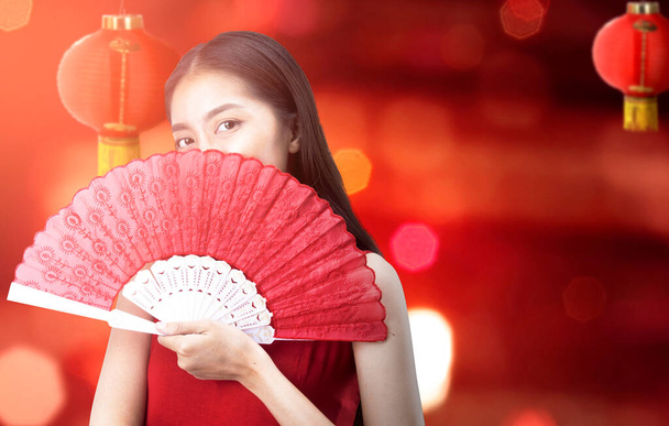 Asian Chinese woman in a cheongsam dress holding fan celebrates Chinese New Year. Happy Chinese New Year - Фото, изображение