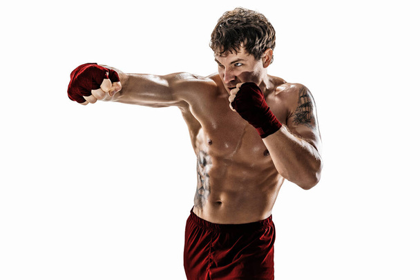 Studio shot of kickboxer who training, practicing jab on white background. Red sportswear - Photo, image