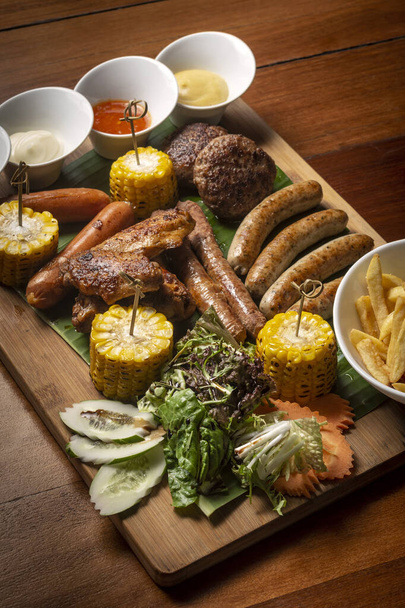 Plateau de viande mixte barbecue avec boulettes de viande, saucisses et ailes sur fond de bois - Photo, image