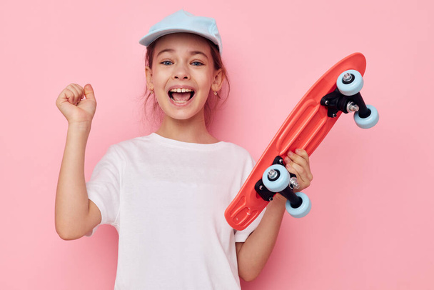 Portrait of happy smiling child girl with a skateboard in hand isolated background - Foto, Imagen