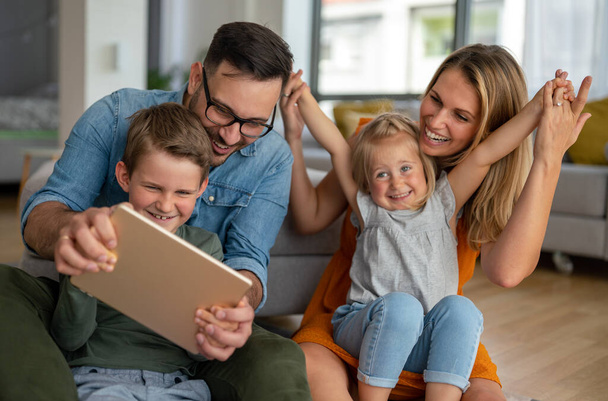 Happy young family having fun time at home. Parents with children using tablet. People love happiness concept. - Foto, Imagem