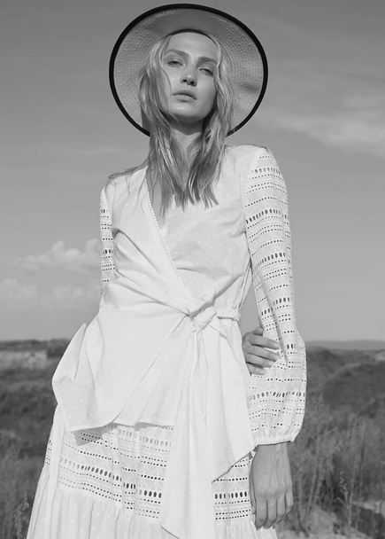 Gorgeous young woman in white romantic clothes on the summer field. Sunny day. Blonde model with big beautiful eyes and nice lips. Calm and balance. Fashionable. Black and white. Emotional portrait. - Foto, Imagem