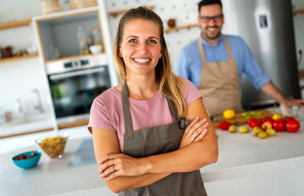 Young happy couple is enjoying and preparing healthy meal in their kitchen together. People food happiness concept. - Foto, Bild