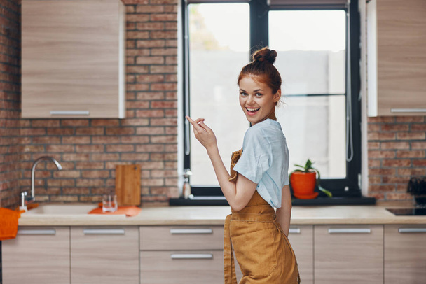 pretty woman in a brown apron kitchen interior modern style - Foto, imagen
