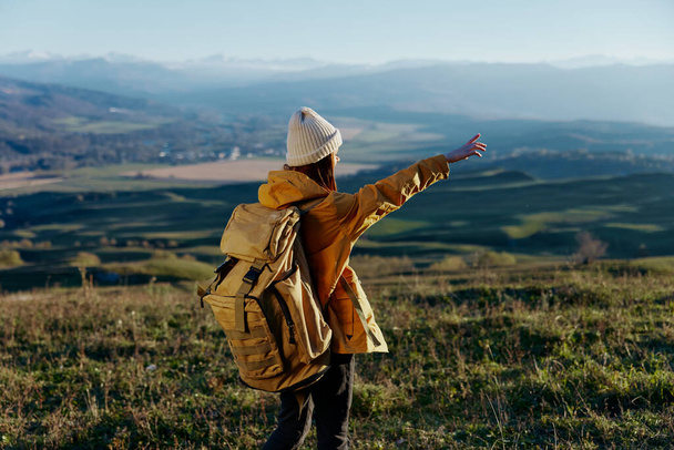 vrouw toerist in een gele jas in een hoed rugzak reizen bergen frisse lucht - Foto, afbeelding