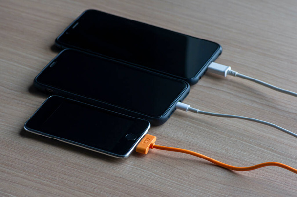 Telefones inteligentes móveis carregando na mesa de madeira - Foto, Imagem