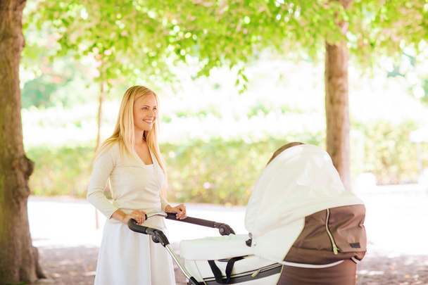 happy mother with stroller in park - Photo, Image