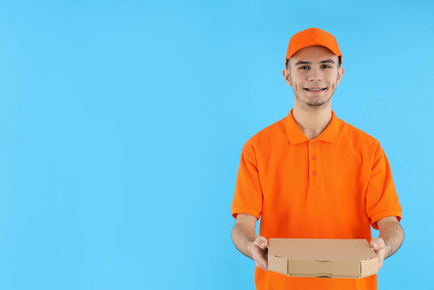 Attractive delivery man with pizza box on blue background - Photo, Image