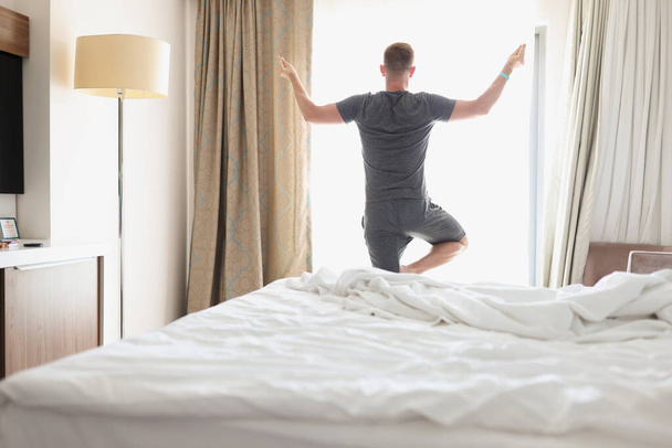 Egy férfi jógázik az ablak előtt reggel. - Fotó, kép